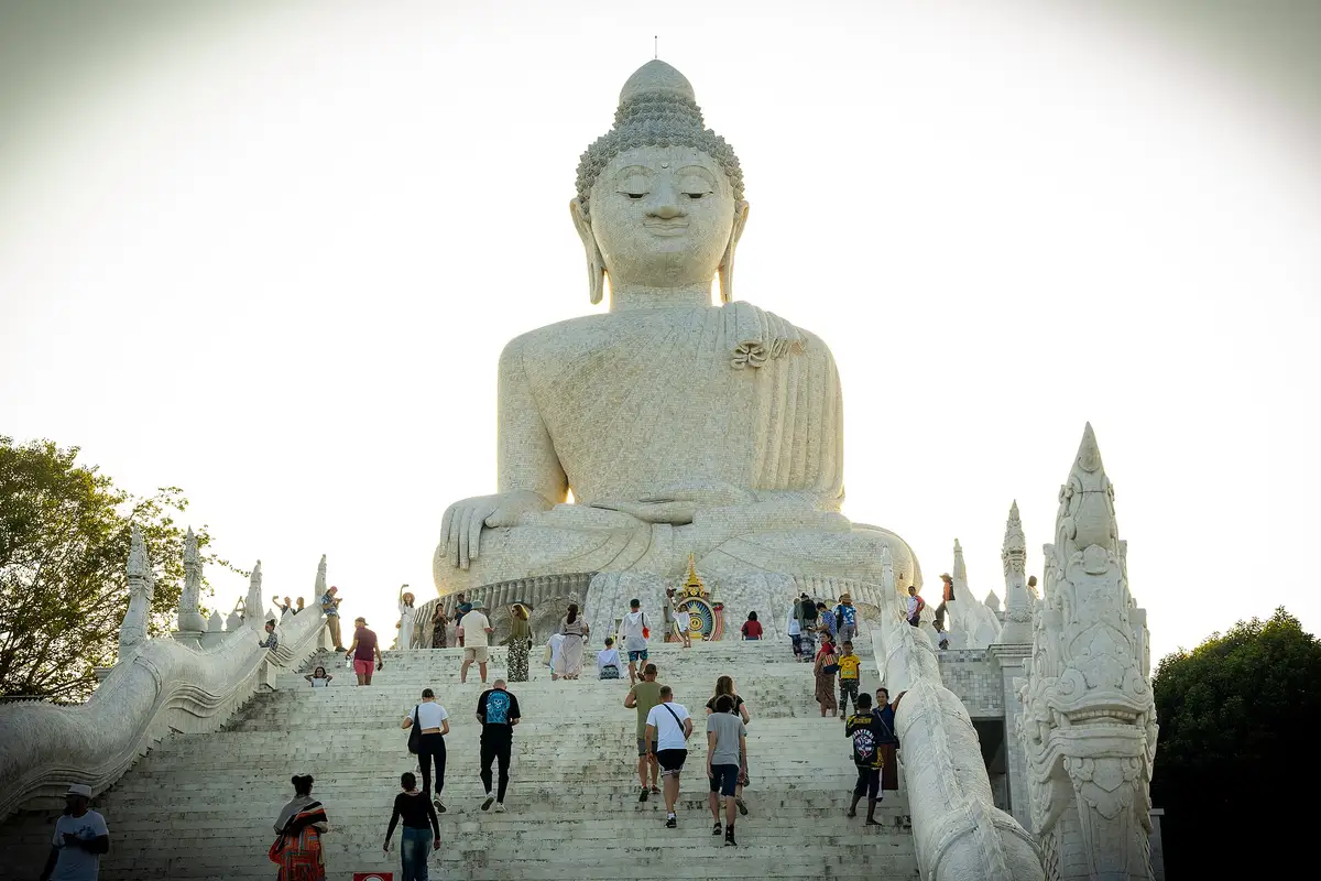 Visitors climbing the wide marble staircase to Big Buddha Phuket between white naga serpent balustrades