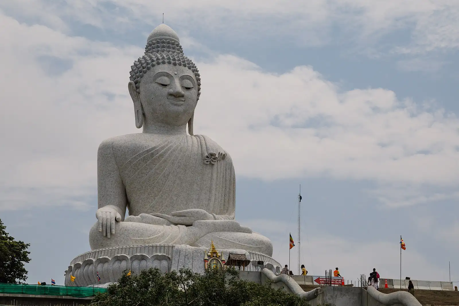 The seated white marble Big Buddha of Phuket on its lotus base against a blue sky with scattered cloud